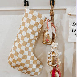 Festive holiday decor with checkered stocking and decorative hanging bells on a white wall.
