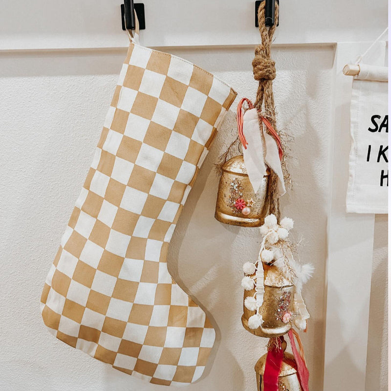 Festive holiday decor with checkered stocking and decorative hanging bells on a white wall.