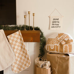 Cozy holiday fireplace with stockings, gingerbread decor, and festive greenery.