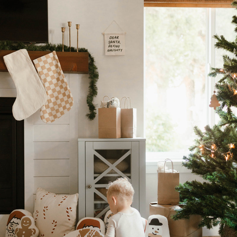Cozy Christmas living room with stockings, holiday decorations, and a child near the Christmas tree.