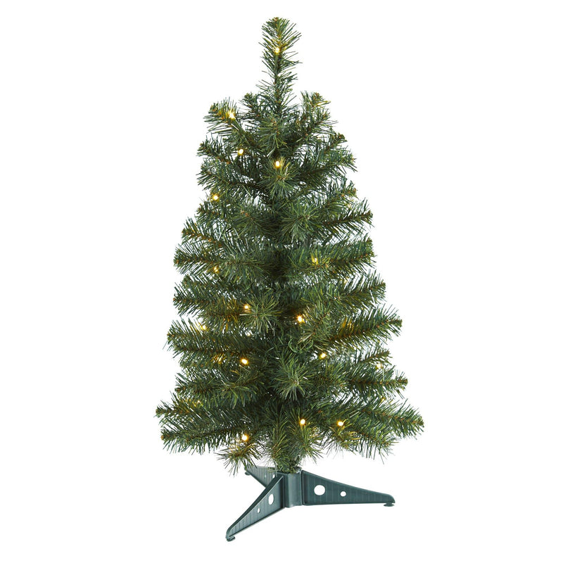 Small prelit artificial Christmas tree with warm white LED lights and realistic pine needles on a green plastic stand, tabletop holiday decoration