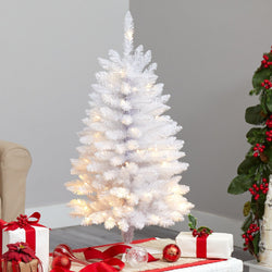 Pre-lit white artificial tabletop Christmas tree with warm white LED lights, surrounded by red and white wrapped gifts, ornaments and holiday greenery in cozy living room décor