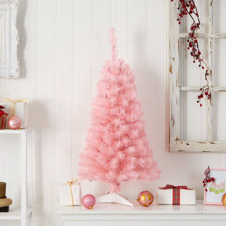 Pink artificial Christmas tree on white shelf with wrapped gifts, pink and gold ornaments and red berry garland — festive holiday tabletop decor