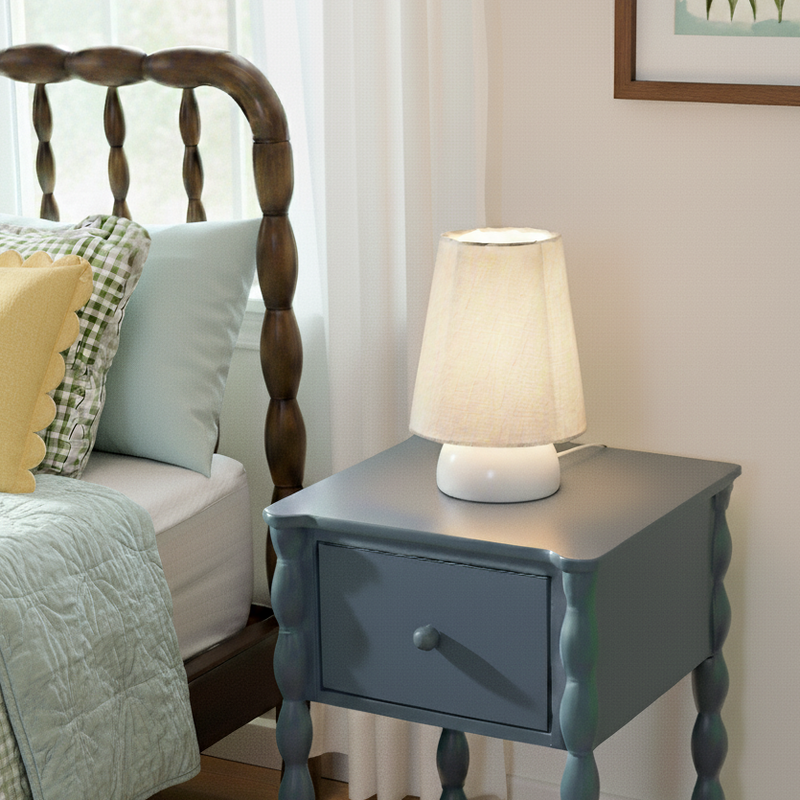 Blue nightstand with a lamp next to a bed with pillows and a wooden headboard.