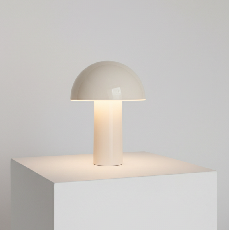 Small table lamp with a beige shade on a white cube against a light gray background
