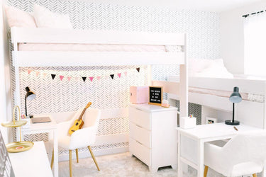 Bright modern kids' bedroom with white twin loft bunk beds, two study desks, chevron wallpaper, string bunting and ukulele