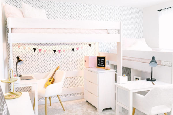 Bright modern kids' bedroom with white twin loft bunk beds, two study desks, chevron wallpaper, string bunting and ukulele