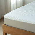 Close-up of white quilted mattress on wooden bed frame in bright minimalist bedroom, textured wavy mattress cover