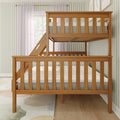 Natural oak solid wood twin-over-full bunk bed with slatted guardrails and angled ladder in bright children's bedroom with pale green striped wallpaper
