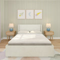 Children's bedroom with upholstered white bed, textured mattress, wooden nightstands with blue lamps, green striped wallpaper and framed rocket, moon and shooting star prints