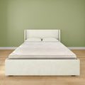 Minimalist modern bedroom with white upholstered platform bed and mattress, two pillows, light wood floor and soft green painted wall