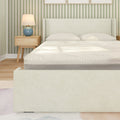 Modern white upholstered bed with textured memory foam mattress, wooden nightstand and blue lamp in green striped bedroom
