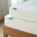 Close-up of stacked 8-inch gel memory foam mattresses with white quilted cover on a wooden bed frame