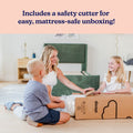 Family mattress unboxing with safety cutter — mother and two kids unpacking a boxed mattress next to a green upholstered bed frame