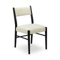 Cream boucle upholstered dining chair with rounded seat and black metal frame on white background