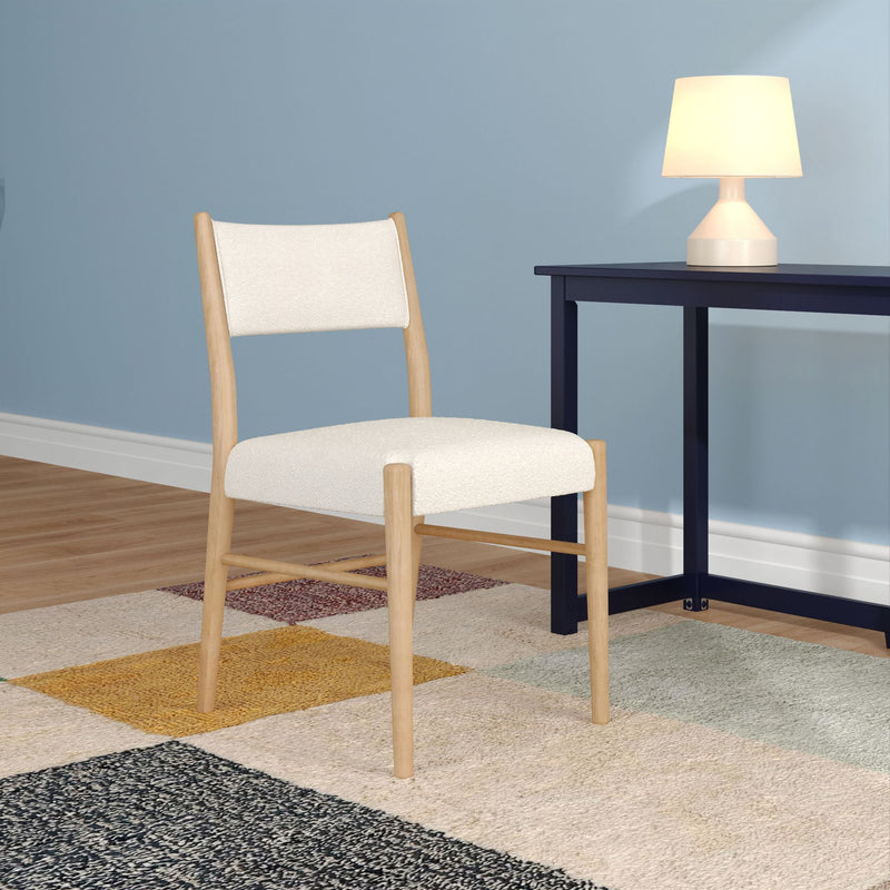 Minimal Scandinavian dining chair with white upholstered seat beside navy side table and lit table lamp against a blue accent wall on hardwood floor with geometric rug