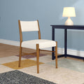 Mid-century modern wooden dining chair with cream upholstery next to navy side table, white table lamp and multicolor area rug against a blue wall