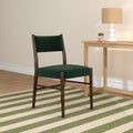 Green upholstered accent chair with dark wood frame beside a light-wood side table holding a white sculptural lamp and potted succulent in a neutral living room