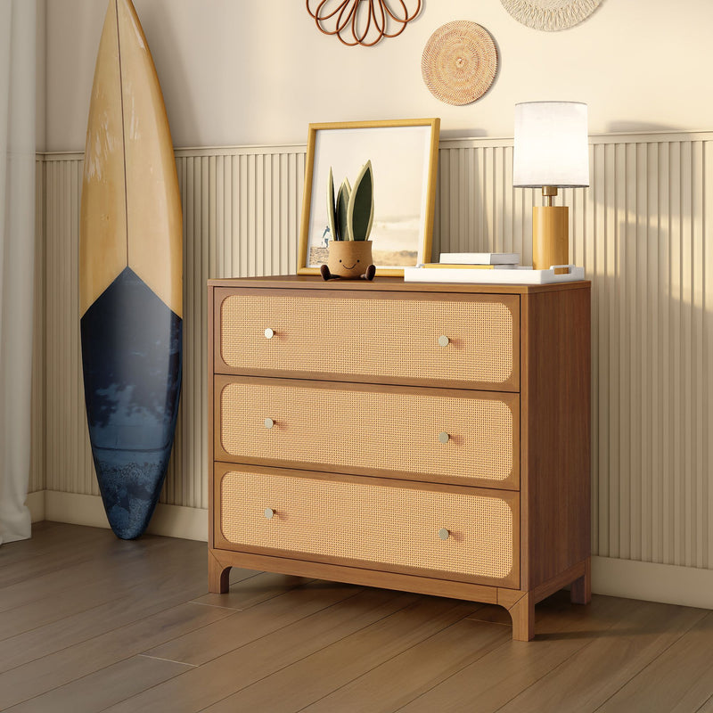Mid-century modern three-drawer rattan dresser in coastal bedroom with surfboard, table lamp, potted succulent, wall decor and hardwood floors