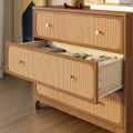 Mid-century modern walnut dresser with woven rattan (cane) drawer fronts and brass knobs, open drawer revealing neatly folded knit clothes on hardwood floor