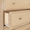 Close-up of light wood chest of drawers with woven cane rattan drawer fronts, brass round knob and a partially open drawer