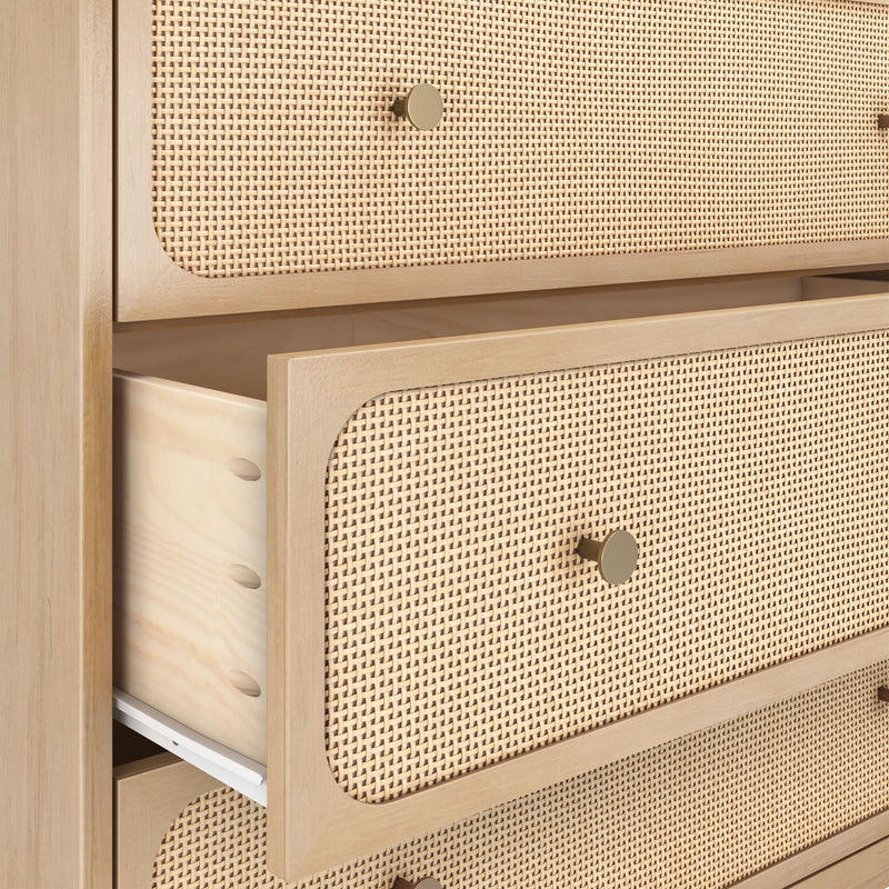 Close-up of light wood chest of drawers with woven cane rattan drawer fronts, brass round knob and a partially open drawer