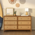Six-drawer mid-century wood dresser with woven rattan cane drawer fronts, coastal boho bedroom styling with surfboard, table lamp, framed beach photo and potted plant