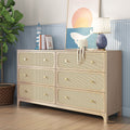 Light wood six-drawer rattan-front dresser with brass knobs on blue beadboard wall, coastal nursery styling with table lamp, framed whale print, plush octopus and potted fiddle-leaf fig