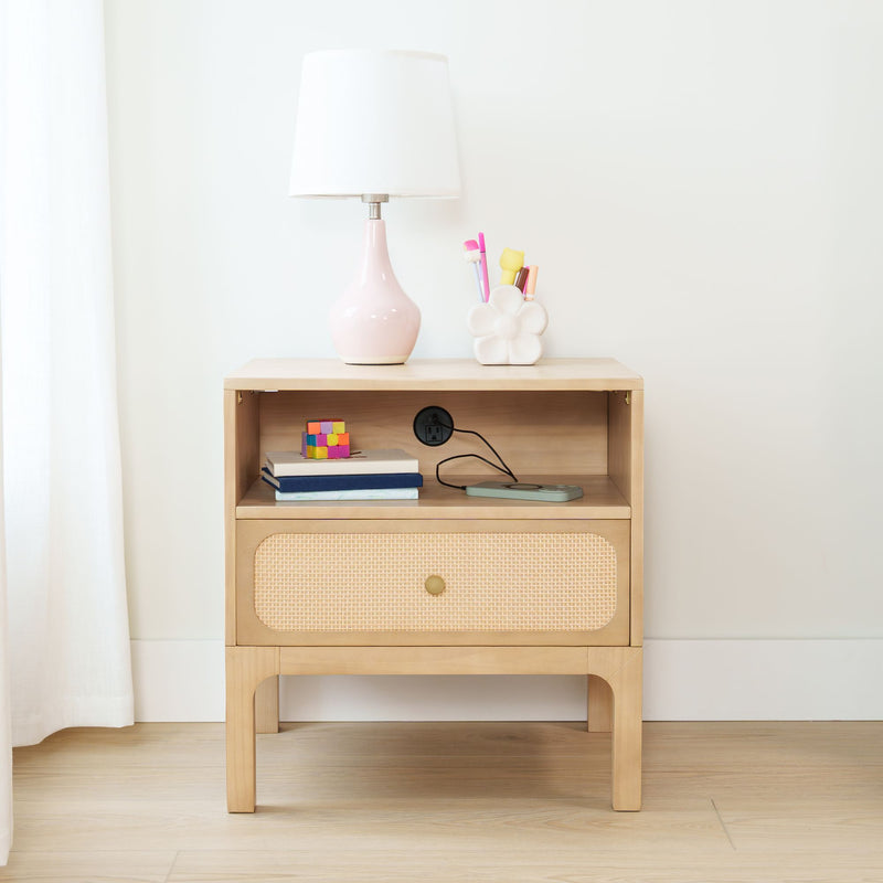 Minimalist light-wood nightstand with pink ceramic bedside lamp, rattan drawer, flower pen holder with colorful pens, books and toy