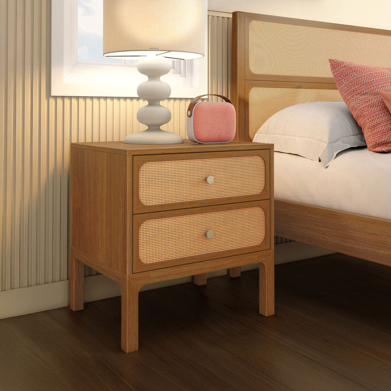 Modern wooden bedside table with rattan drawer fronts, white table lamp and pink Bluetooth speaker beside bed in cozy bedroom