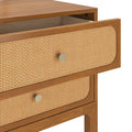 Mid-century modern wooden bedside table with woven rattan cane drawer fronts, brass round knobs, warm wood finish and open top drawer