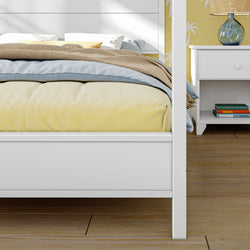 Contemporary bedroom with a white bedframe, soft yellow bedding, and a wooden nightstand with books, perfect for modern home decor inspiration.