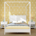 White four-poster canopy bed with blue and yellow bedding against yellow palm-print wallpaper, white nightstands and lamps — modern coastal bedroom interior