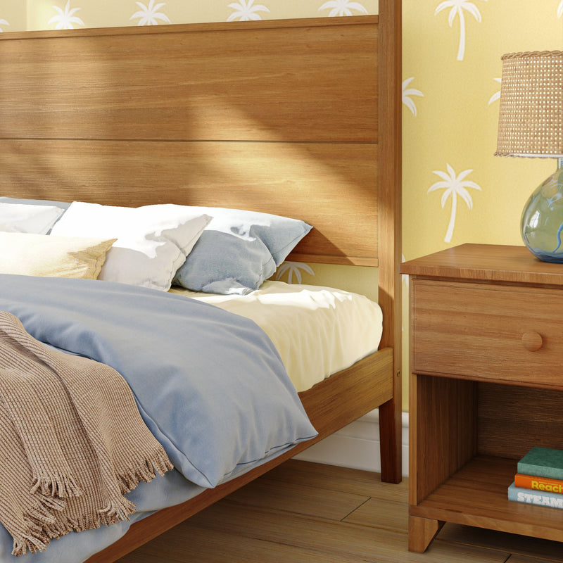 Cozy bedroom with a wooden bed frame, soft pillows, and a nightstand featuring a decorative lamp, creating a relaxing atmosphere.