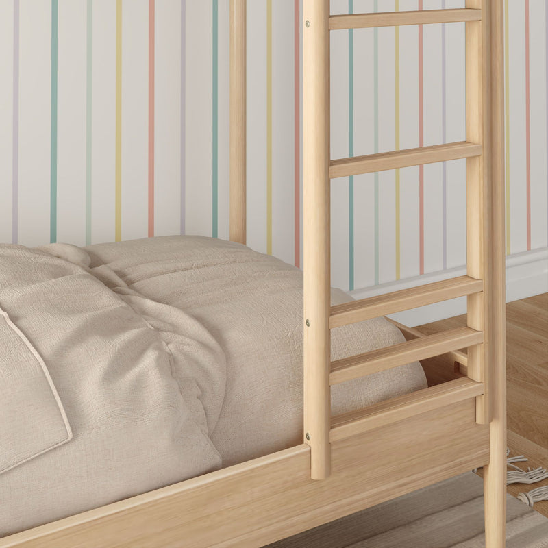 Close-up of natural wood bunk bed ladder and beige quilted bedding against pastel rainbow-striped wallpaper in a cozy children's bedroom.