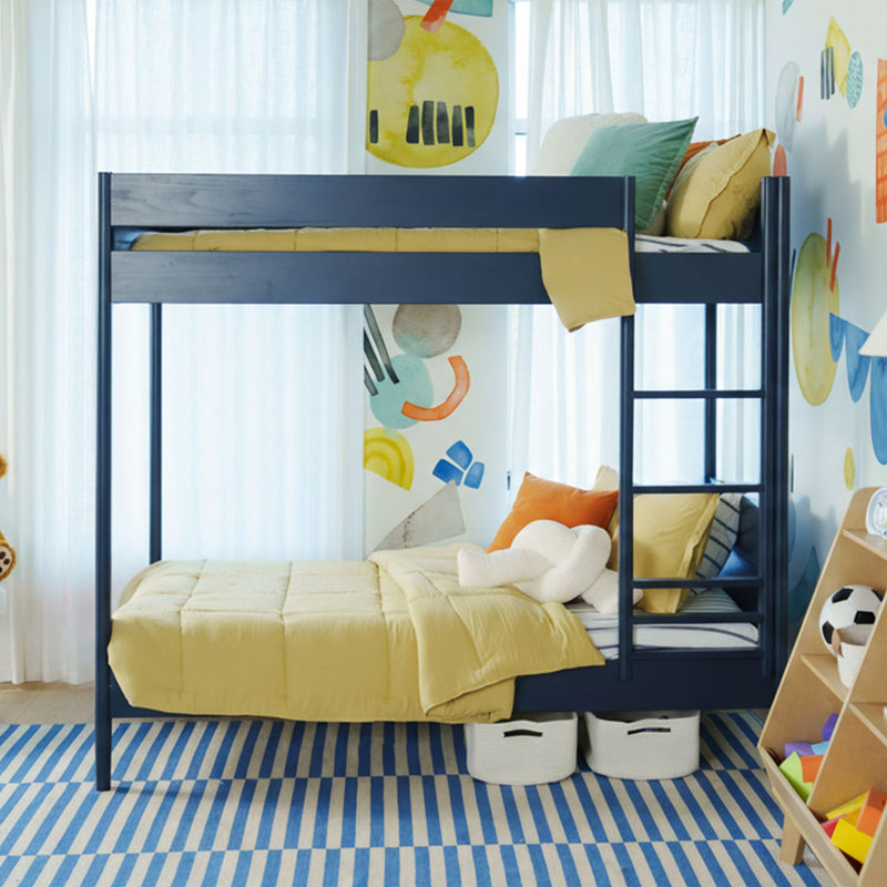 Modern navy blue kids bunk bed with yellow bedding, striped rug, colorful wall art and under-bed storage baskets in a playful children's bedroom