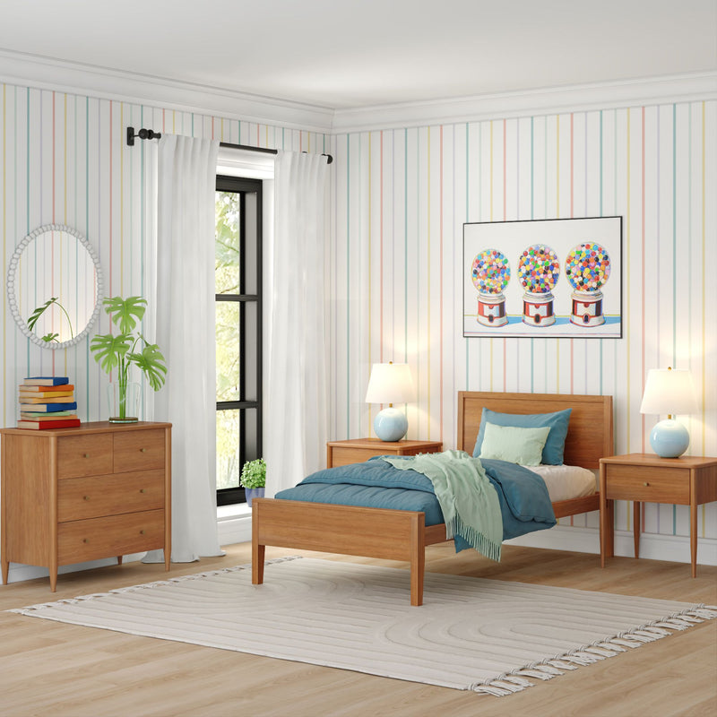 Children's bedroom with mid-century wooden twin bed and blue bedding, pastel striped wallpaper, colorful gumball machine wall art, matching nightstands with lamps, wooden dresser and mirror, houseplant by a sunlit window, light hardwood floor and neutral area rug