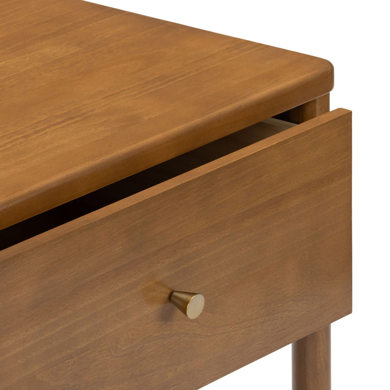 Mid-century modern oak-finish bedside table with single open drawer and brass cone knob, close-up of warm wood grain.