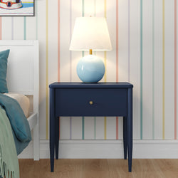 Modern bedroom interior with navy blue bedside table, light blue ceramic lamp, pastel striped wallpaper, white bed frame and wooden floor