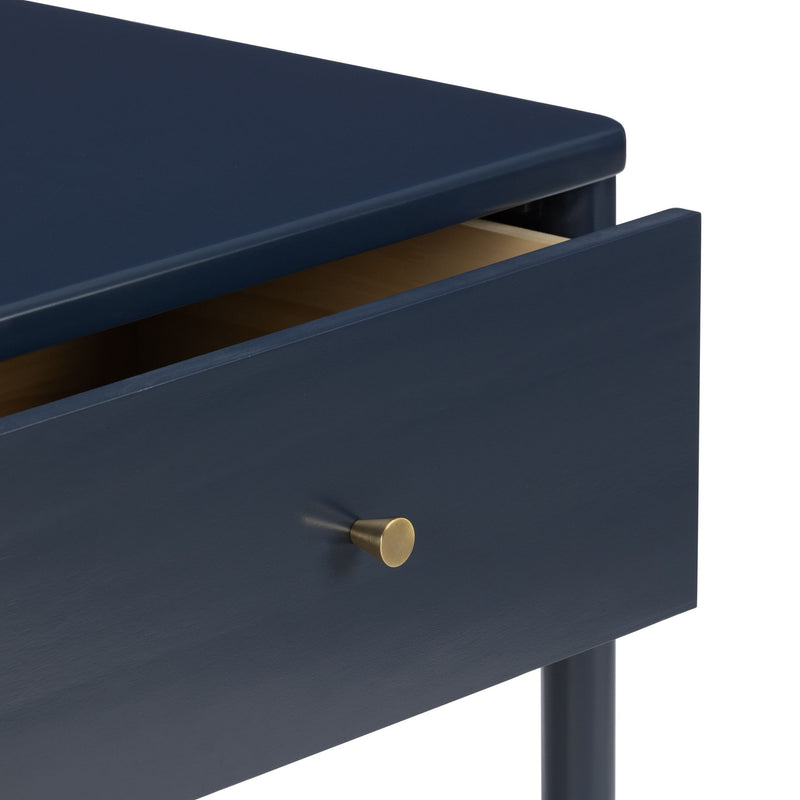 Modern navy blue bedside table with one wooden drawer, brass knob, and round tapered legs