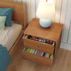 Wooden nightstand with light-blue lamp and two open drawers showing children's toys and colorful books beside a wooden bed