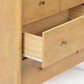 Light natural pine dresser with partially open drawer revealing interior wood joinery, metal drawer slide and brass-finish cone knobs, modern bedroom storage
