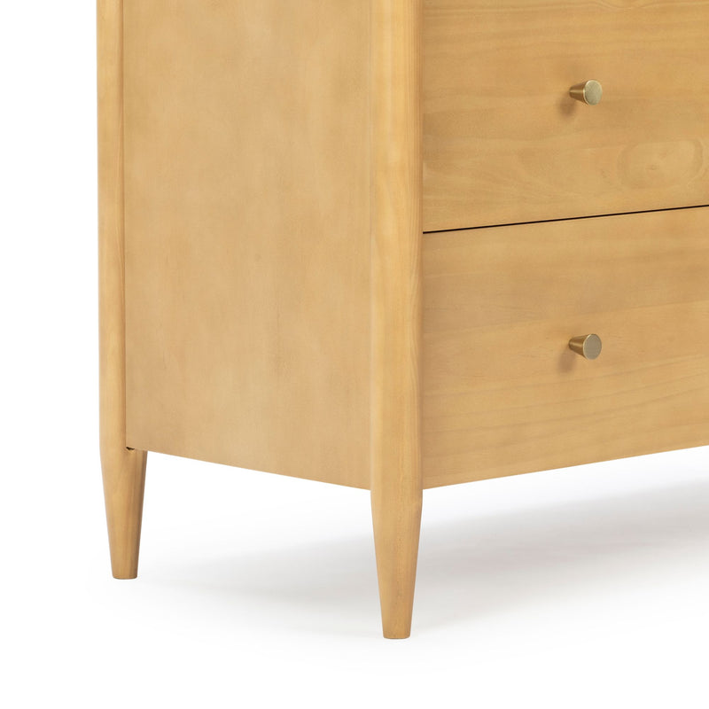 Close-up of a light-wood mid-century modern dresser with tapered legs and brass round drawer knobs, natural finish bedroom furniture