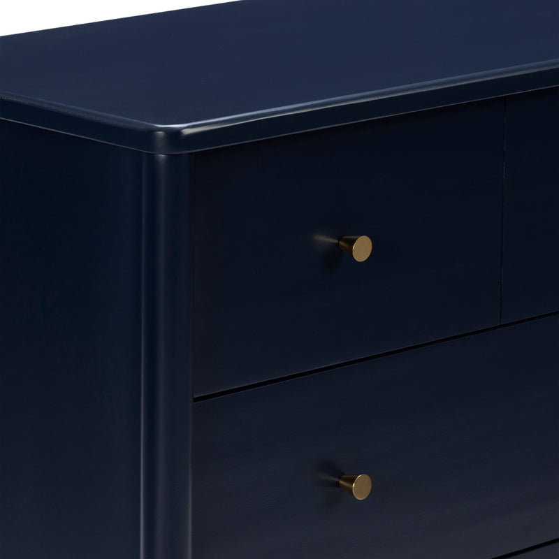 Close-up of navy blue wooden dresser with gold round drawer knobs, modern bedroom chest of drawers