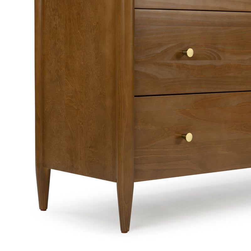 Close-up of a mid-century modern walnut-toned wooden dresser corner with two drawers, round brass knobs and tapered legs for bedroom storage