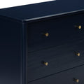Close-up of navy blue painted wooden dresser with round brass knobs — modern chest of drawers for bedroom storage and décor