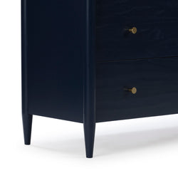 Navy blue mid-century modern dresser corner with tapered legs and brass drawer knobs, bedroom storage chest