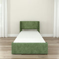 Green upholstered single platform bed frame with white mattress in modern minimalist bedroom on light wood floor