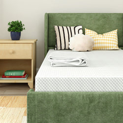 Green upholstered bed with patterned pillows and cozy blanket in modern bedroom setting.