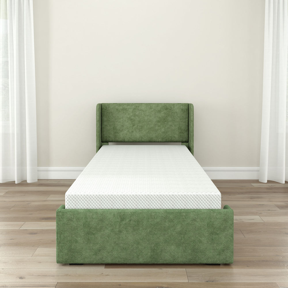 Green upholstered single bed frame with white mattress in a minimalist bedroom setting.